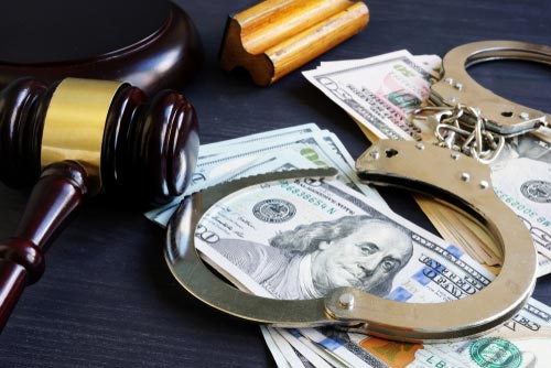 Gavel, handcuffs and hundred-dollar bills on a table