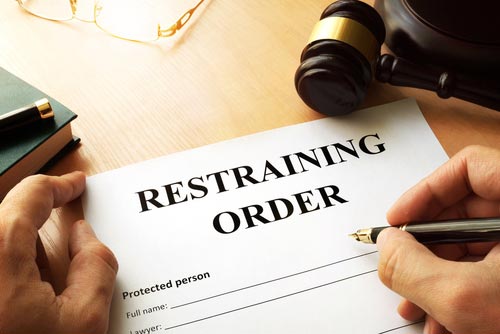 Hand with a pen completing a restraining order form