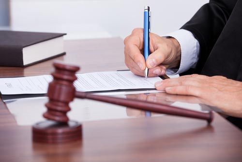 Judge writing on court papers beside a gavel